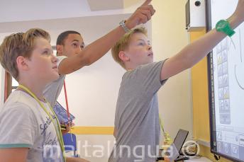 Un insegnante aiuta 2 studenti alla lavagna interattiva