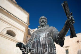Una statua a Malta di un uomo che tiene un rotolo