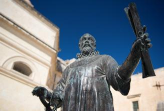 Una statua a Malta di un uomo che tiene un rotolo