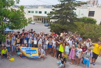 Un gruppo di giovani studenti salutano fuori della scuola estiva
